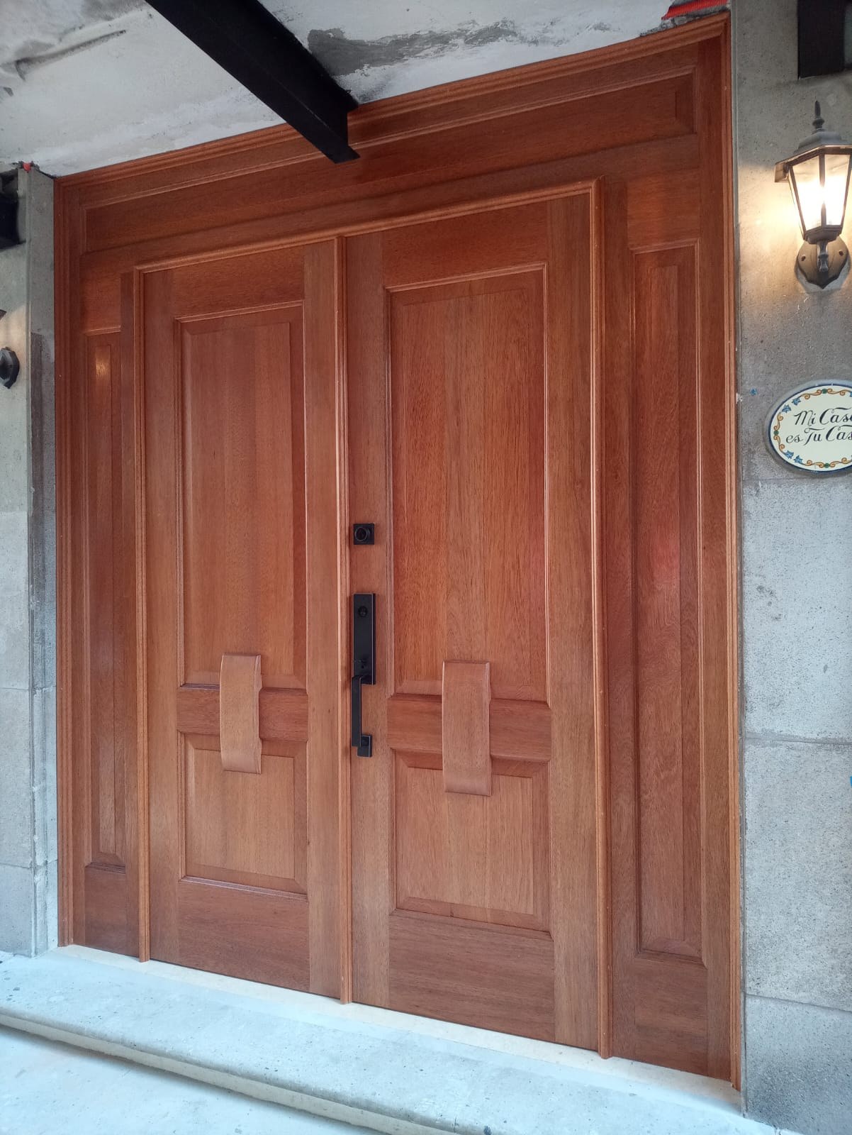 Puerta doble de madera con paneles y herrajes oscuros