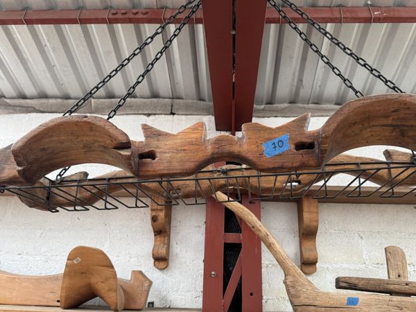 Piezas de madera de perfiles curvos y angulares sobre un soporte metálico suspendido con cadenas.