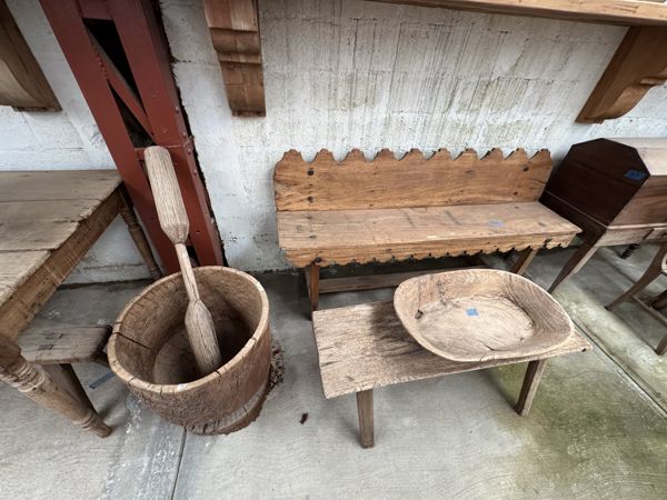Banca de respaldo recortado detrás de un recipiente profundo con una pieza alargada de madera y una fuente ovalada sobre una mesa baja.