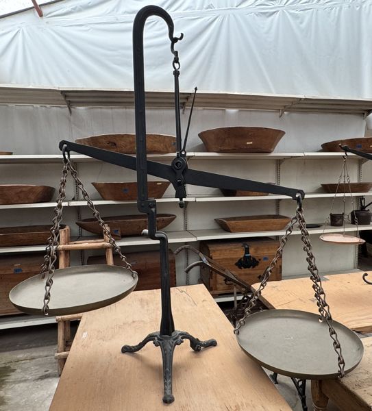 Balanza de metal con platillos suspendidos por cadenas y base de tres patas.