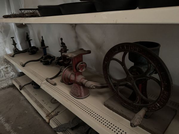 Aparatos metálicos agrupados en una repisa, incluido uno oscuro con gran rueda de radios y otro rojo con abertura superior ensanchada.