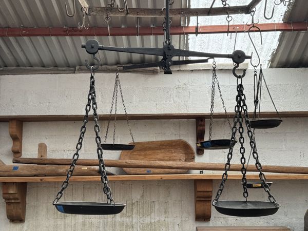 Balanzas suspendidas con barras horizontales, cadenas y platos poco profundos superpuestos en un espacio de almacenamiento.