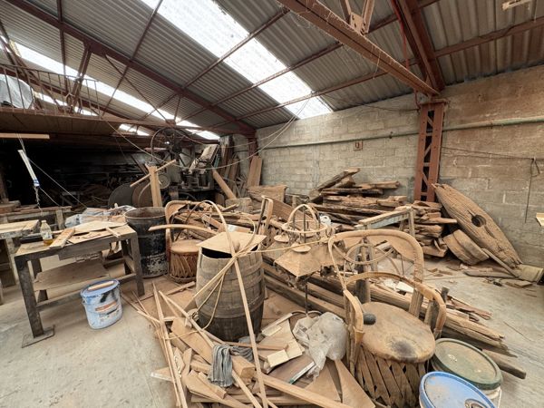 Vista del almacén con ruedas de radios, aros, bastidores y numerosas piezas de madera superpuestas bajo la estructura del techo.