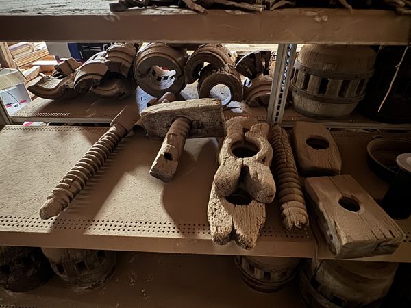 Piezas de madera con roscas grandes, bloques perforados y formas curvas agrupadas en una repisa.