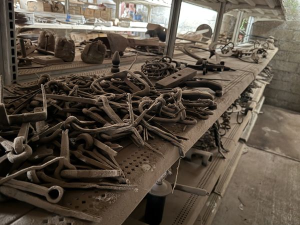 Conjunto de ganchos, eslabones, aros y varillas metálicas amontonados sobre una repisa.