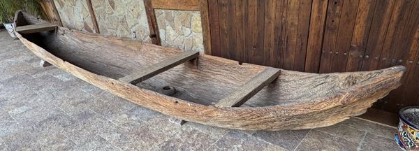 Canoa de madera ahuecada con tablas transversales, exhibida sobre soportes.