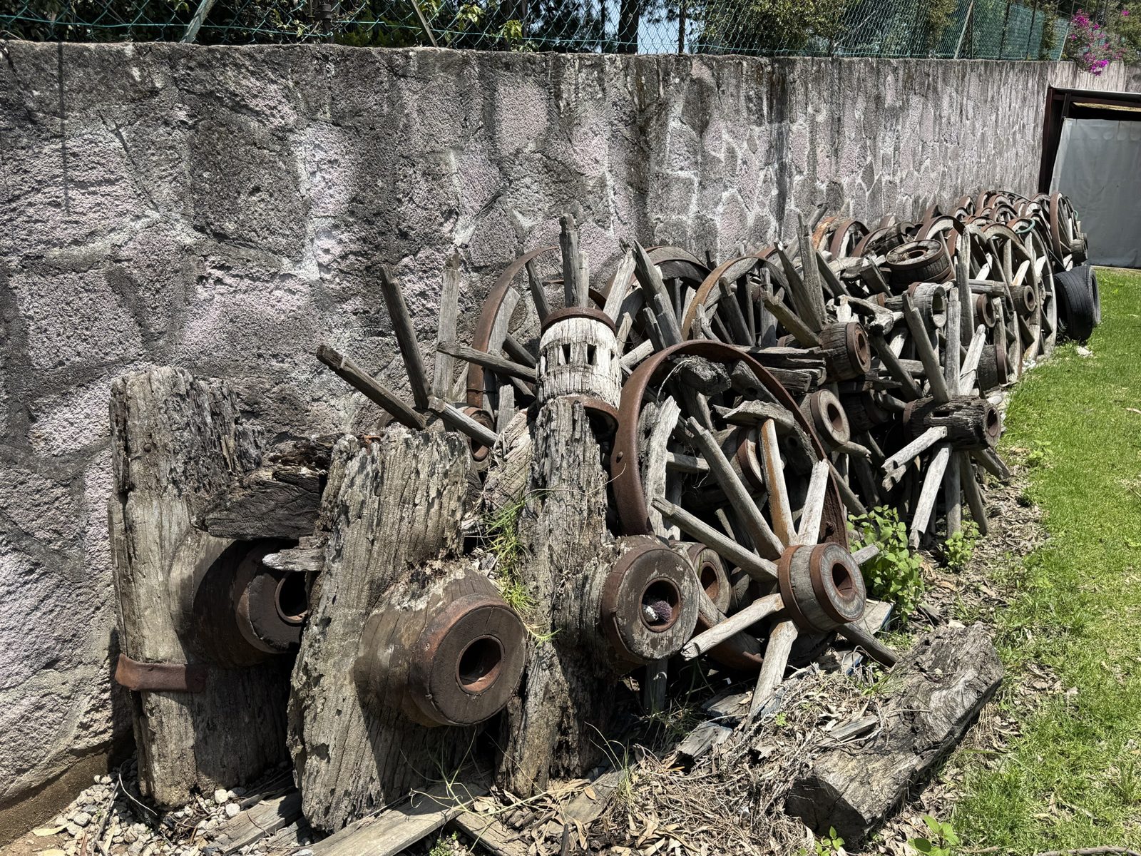 Pila de ruedas de carreta apoyadas en un muro de piedra.