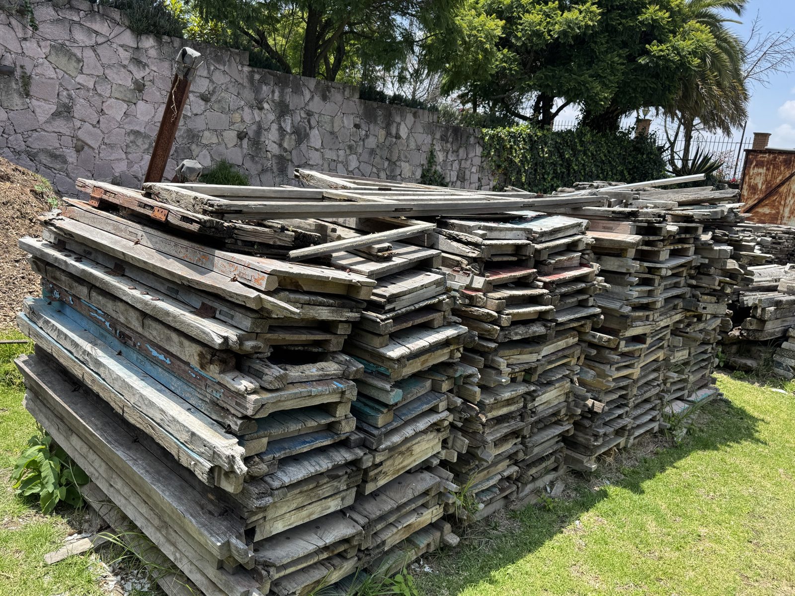 Tablones y tablas pintadas recuperadas, apilados al exterior.