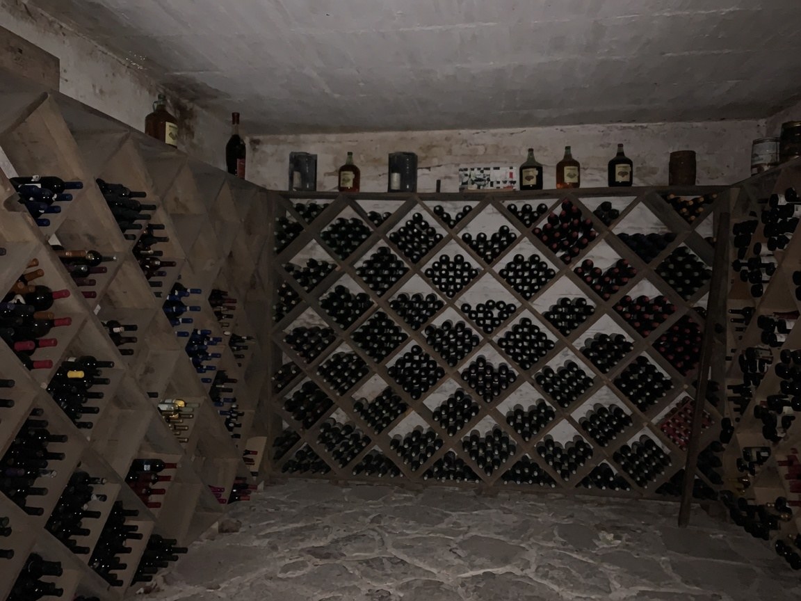 Cava de vinos de Finca La Cima con botelleros de madera y muros de mampostería blanca